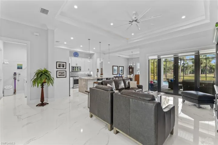 Living room featuring marble finish floor, a tray ceiling, french doors, and ornamental molding