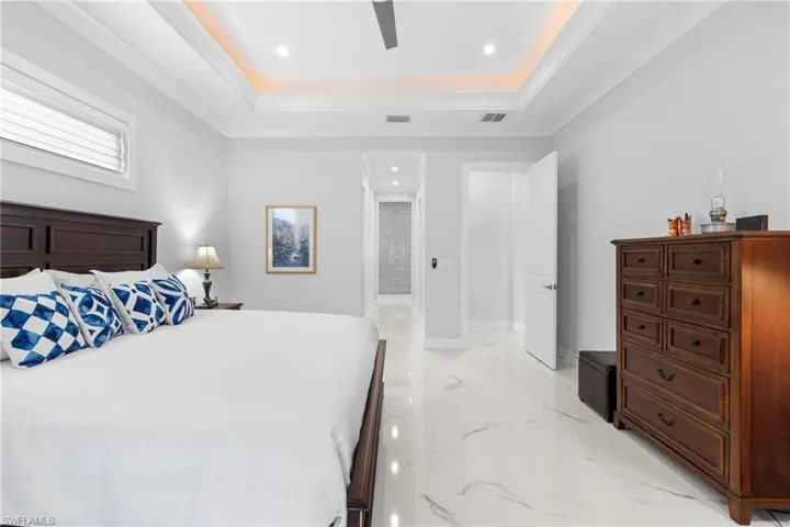 Bedroom featuring a raised ceiling, visible vents, marble finish floor, and baseboards