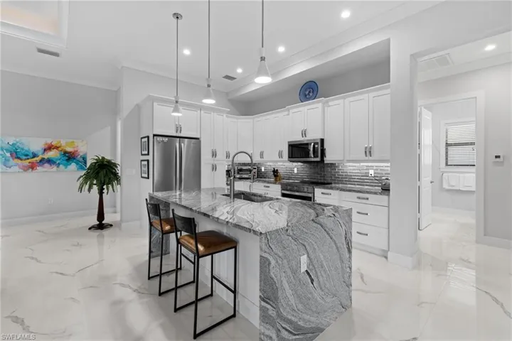 Kitchen featuring appliances with stainless steel finishes, marble finish floor, a sink, and light stone countertops