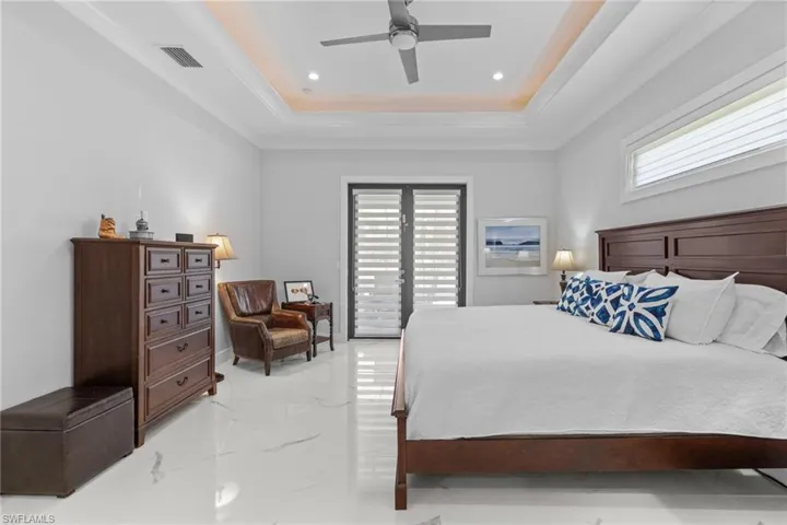 Bedroom featuring a tray ceiling, marble finish floor, visible vents, and recessed lighting