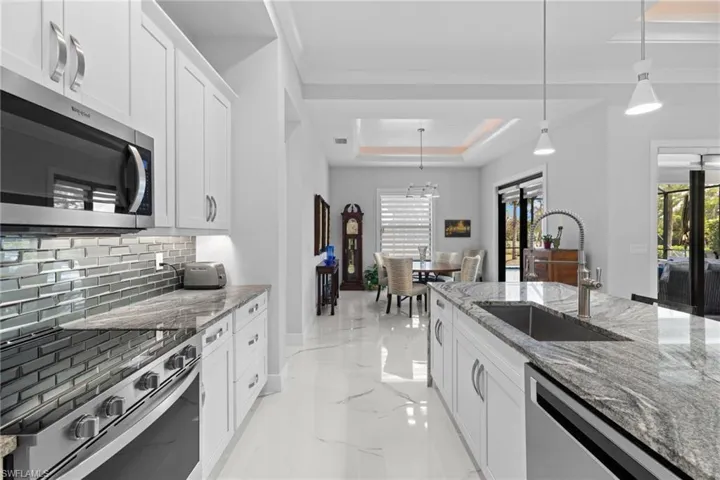 Kitchen with a sink, marble finish floor, appliances with stainless steel finishes, tasteful backsplash, and a raised ceiling