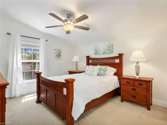 Bedroom with lofted ceiling, light colored carpet, and a ceiling fan
