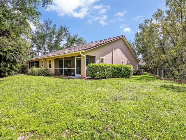 Back of property with stucco siding, a sunroom, and a tiled roof