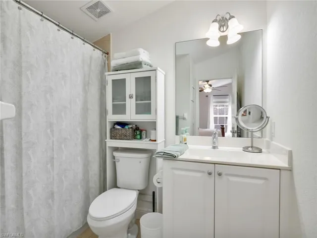 Ensuite bathroom featuring vanity, a shower with curtain, and a ceiling fan