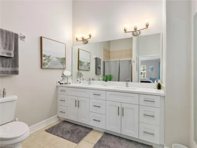 Ensuite bathroom featuring double vanity, light tile patterned flooring, and a stall shower