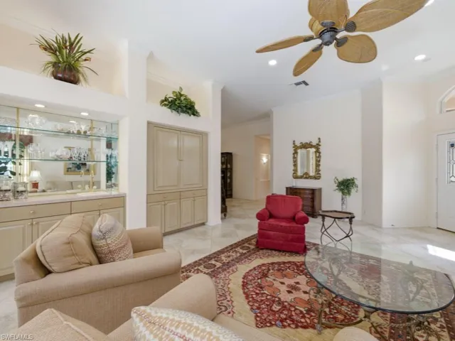 Living area featuring ceiling fan, a high ceiling, recessed lighting, crown molding, and bar