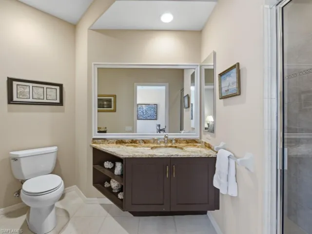 Bathroom with vanity, light tile patterned floors, and tiled shower