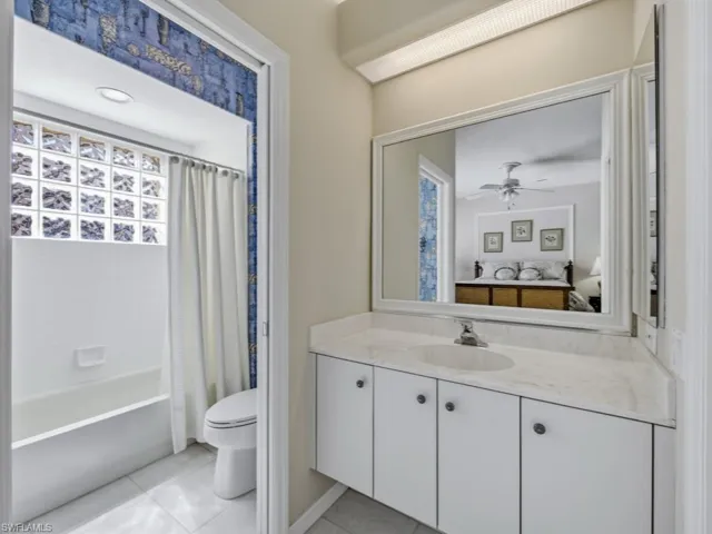 Bathroom with vanity, shower / bathtub combination with curtain, and light tile patterned floors