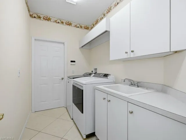 Laundry area with cabinet space, light tile patterned flooring, and washer and clothes dryer