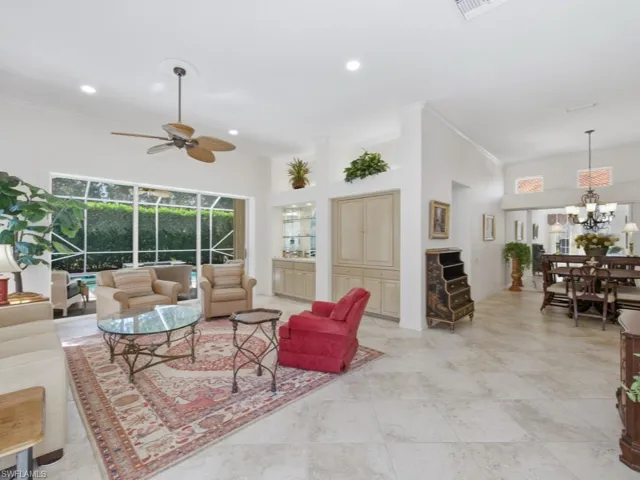 Living room featuring a high ceiling, crown molding, ceiling fan, a sunroom, and suspended lighting