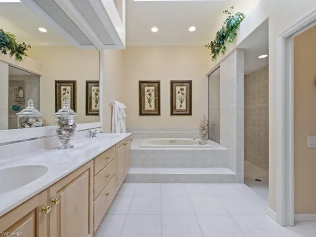 Bathroom featuring walk in shower, double vanity, light tile patterned floors, a garden tub, and ornamental molding