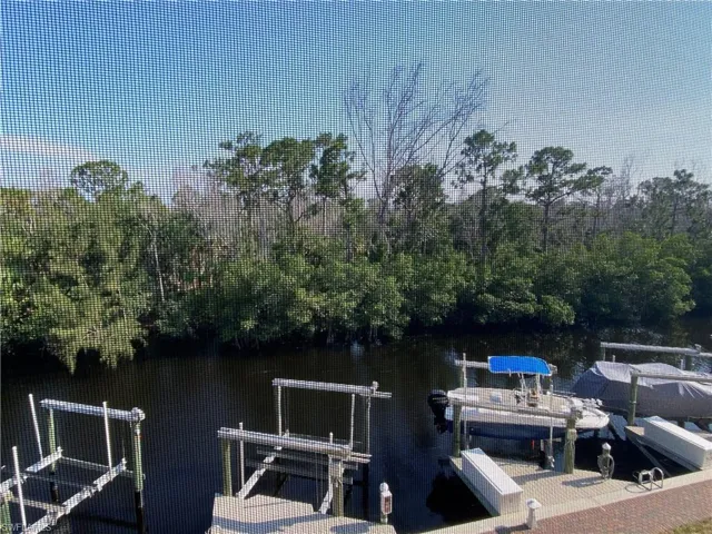 Dock area featuring boat lift, a water view, and a view of trees