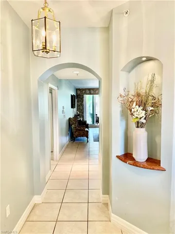 Hall featuring tile patterned flooring, arched walkways, and a chandelier