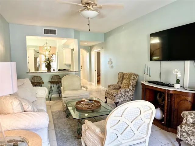 Living area featuring light tile patterned floors, ceiling fan, and a chandelier