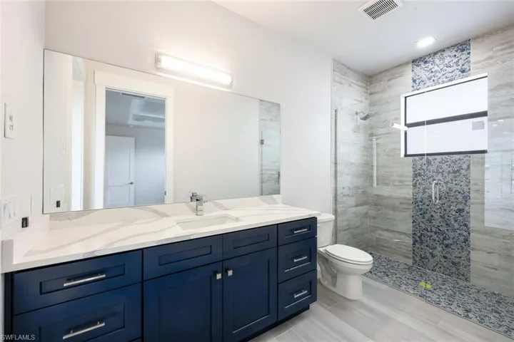 Bathroom featuring vanity, toilet, wood-type flooring, and walk in shower
