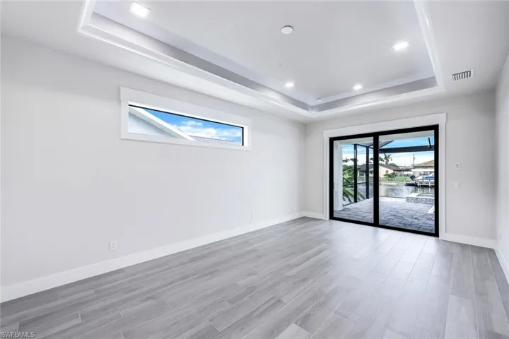 Unfurnished room featuring a wealth of natural light, light wood-type flooring, and a tray ceiling