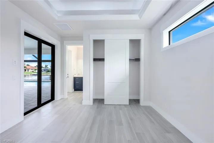 Unfurnished bedroom featuring light hardwood / wood-style flooring, a raised ceiling, a closet, and french doors