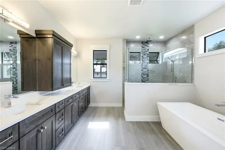 Bathroom featuring hardwood / wood-style floors, vanity, independent shower and bath, and a healthy amount of sunlight