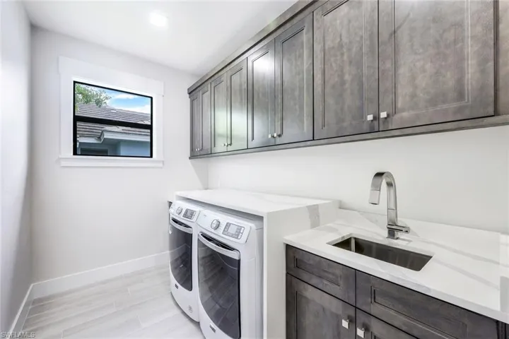 Laundry room with washing machine and dryer, cabinets, sink, and light hardwood / wood-style floors
