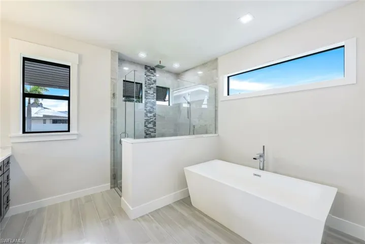 Bathroom with a healthy amount of sunlight, independent shower and bath, hardwood / wood-style floors, and vanity
