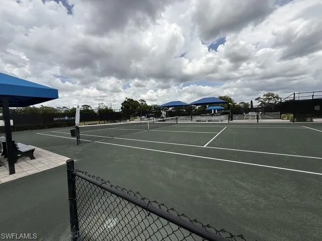 Tennis courts featuring a dark green surface with white line markings, surrounded by black chain-link fencing