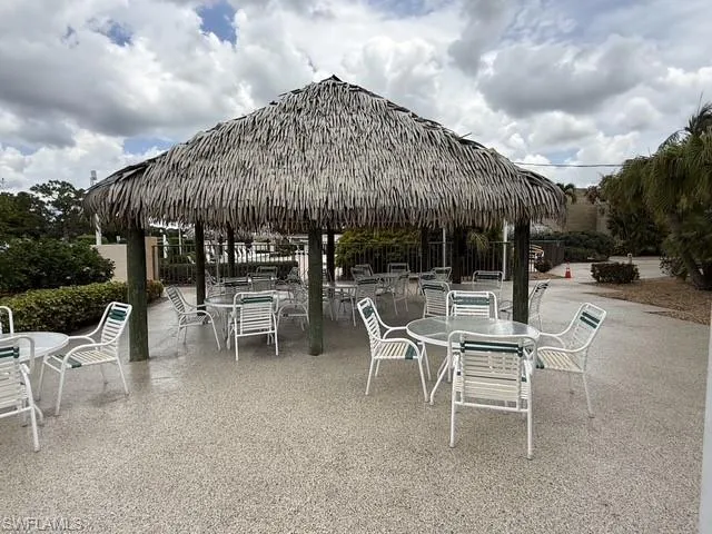 Thatch-roofed pergola with exposed wood support beams and a speckled aggregate concrete patio