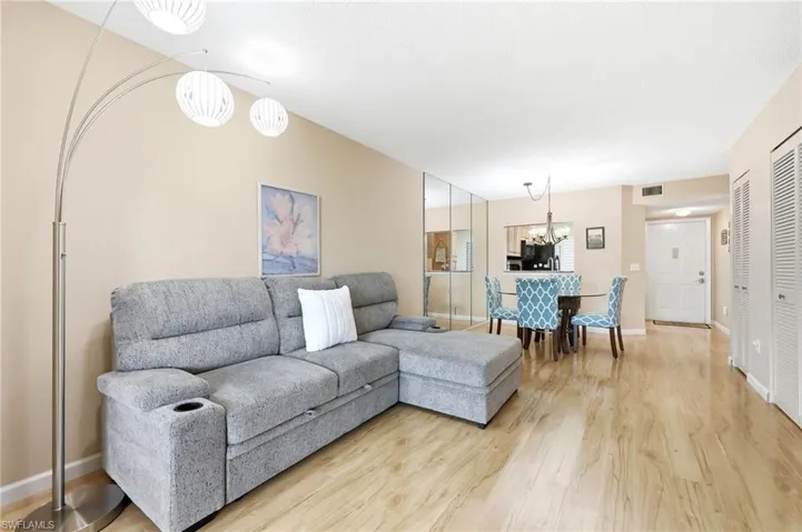 Living area featuring wood-finish flooring, neutral wall tones, and a mirrored accent wall