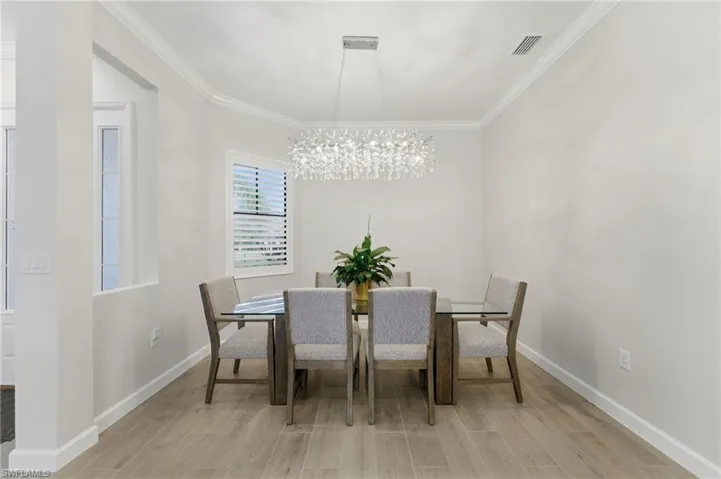 Dining room with wood tiled floors, crown molding, and a chandelier