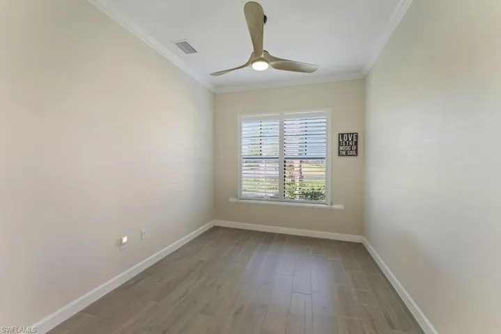 Spare room with wood finished floors, ornamental molding, and a ceiling fan