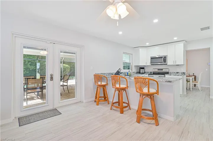 Kitchen with white cabinetry, kitchen peninsula, a wealth of natural light, and stainless steel appliances
