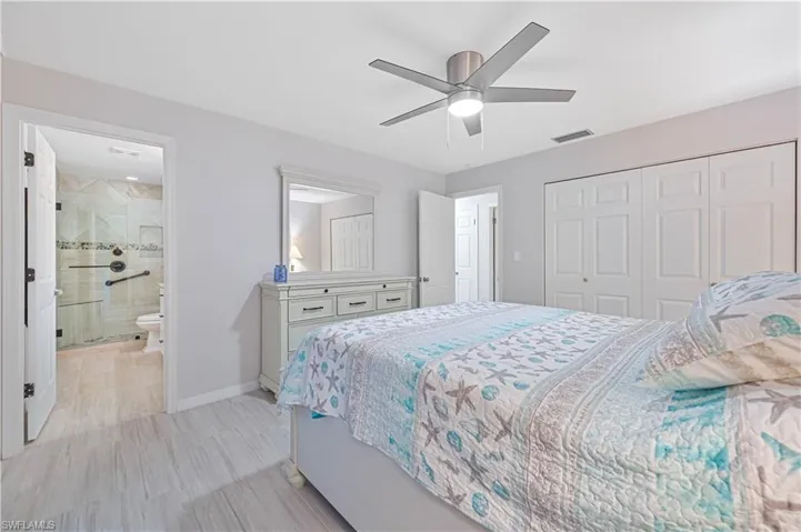 Bedroom featuring a closet, ensuite bath, and ceiling fan