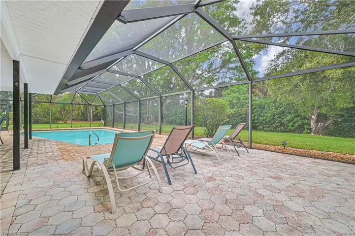 View of swimming pool featuring glass enclosure and a patio