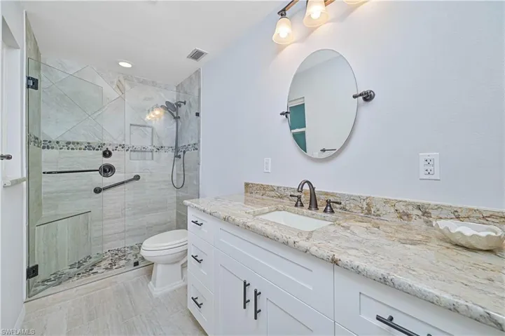 Bathroom featuring vanity, an enclosed shower, and toilet