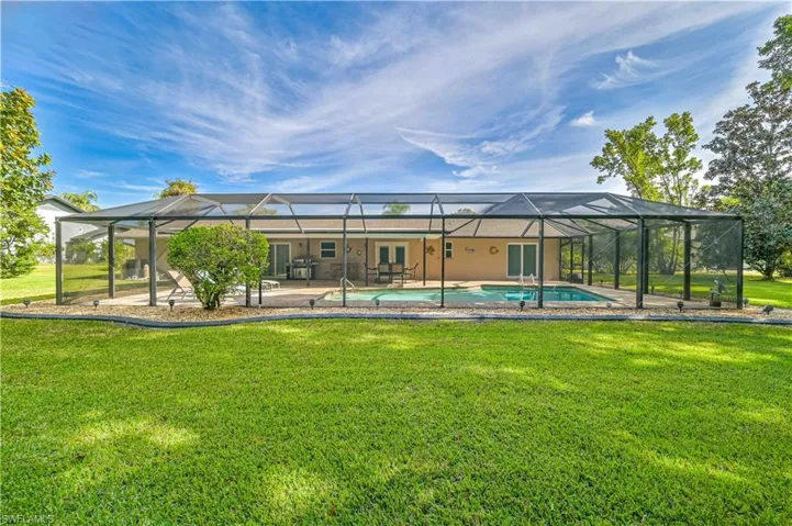 Back of property with a lawn, glass enclosure, and a patio area