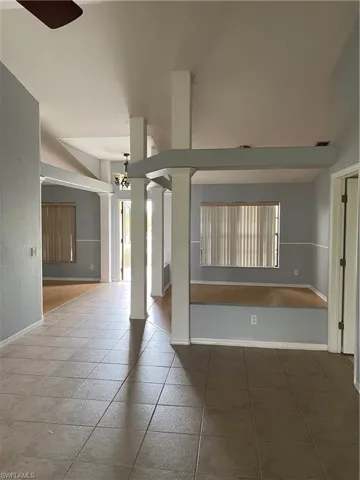 Spacious interior featuring tile flooring, light blue and white wall tones, and elevated ceilings