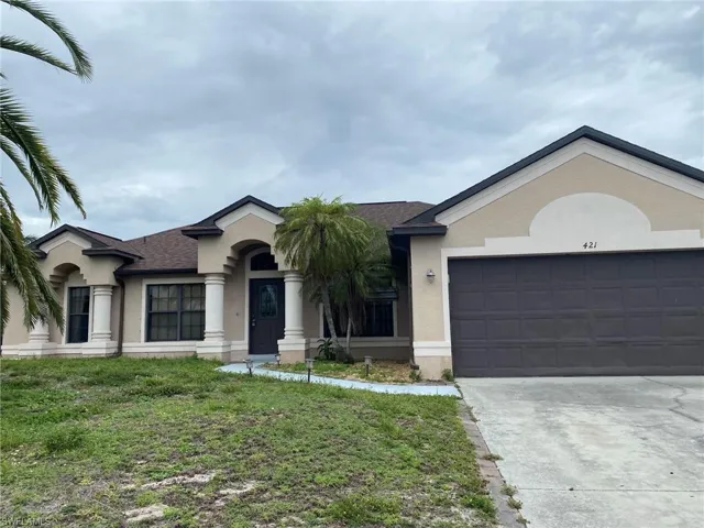 Exterior featuring tan stucco finish, brown roof, and dark brown garage door