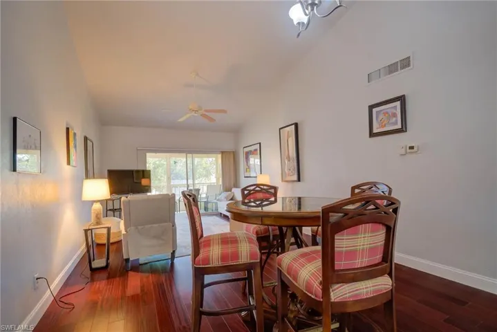 Dining room featuring visible vents, lofted ceiling, baseboards, and hardwood / wood-style floors