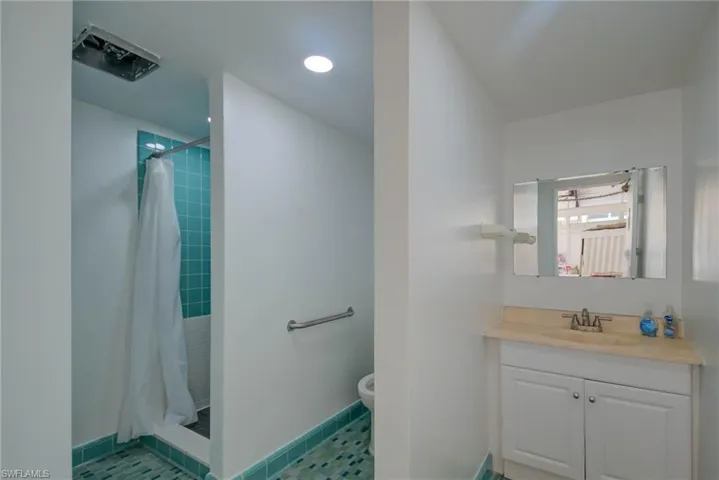 Bathroom with baseboards, toilet, vanity, and a tile shower