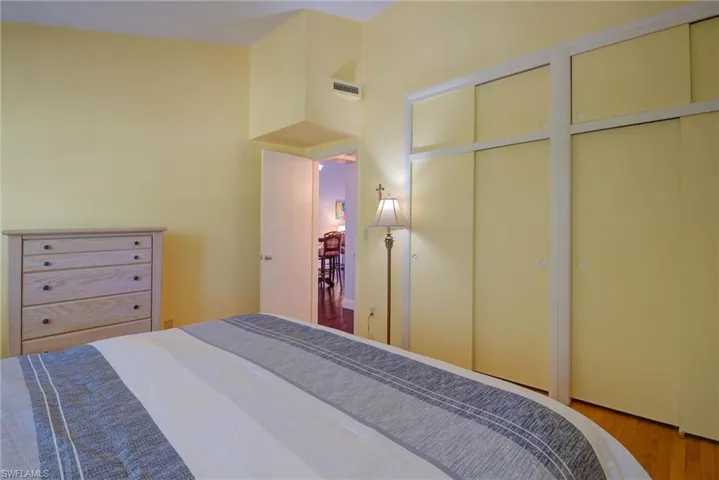 Bedroom with wood finished floors, visible vents, and two closets