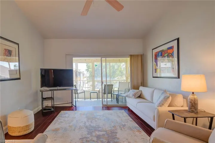 Living room featuring ceiling fan, baseboards, and dark wood-style floors