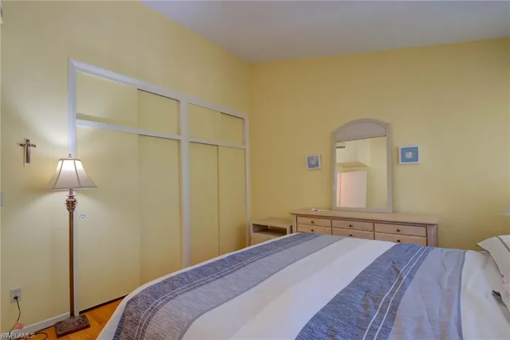 Bedroom with light wood-style flooring, baseboards, and multiple closets