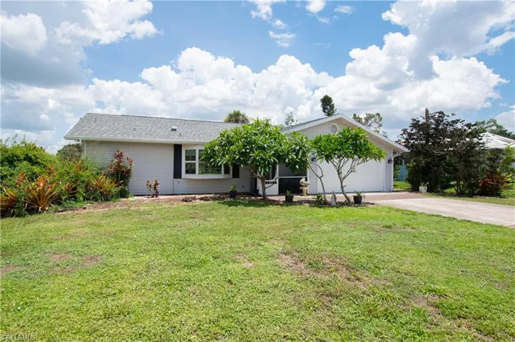 Ranch-style home with concrete driveway, a front lawn, and an attached garage