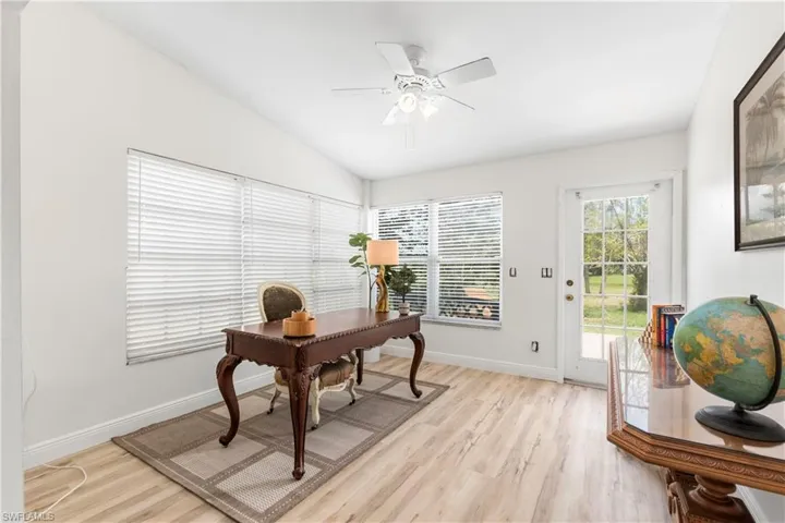 Home office featuring a ceiling fan, light wood-style floors, and vaulted ceiling