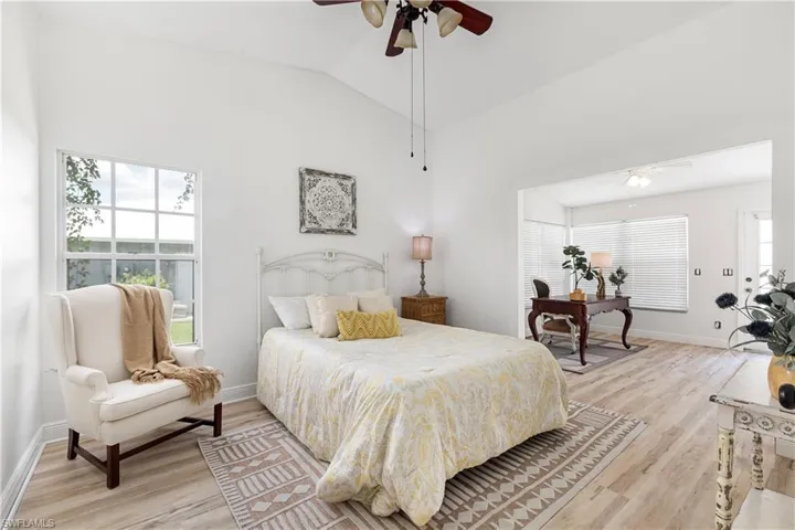 Bedroom with light wood-type flooring, lofted ceiling, and ceiling fan
