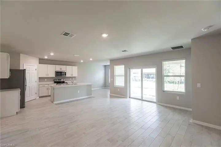 Kitchen with stainless steel appliances, a center island with sink, white cabinetry, and sink