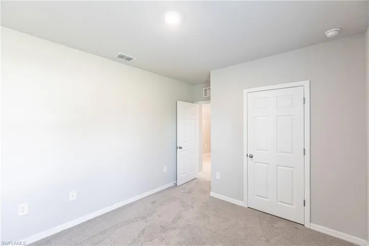 Unfurnished bedroom featuring light carpet and a closet