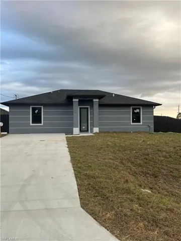 View of front of home featuring roof with shingles and concrete driveway