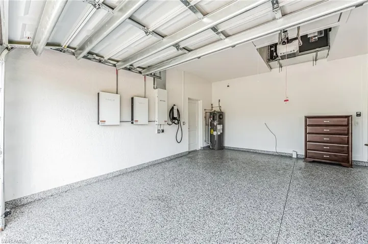 Garage interior featuring a durable epoxy floor, white textured walls, and an overhead garage door