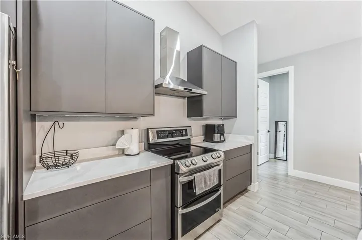 Modern kitchen featuring flat-panel cabinetry, white countertops, stainless steel appliances, and wood-finish tile flooring