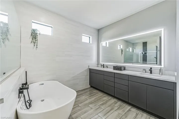 Modern bathroom featuring a freestanding soaking tub and a long double vanity